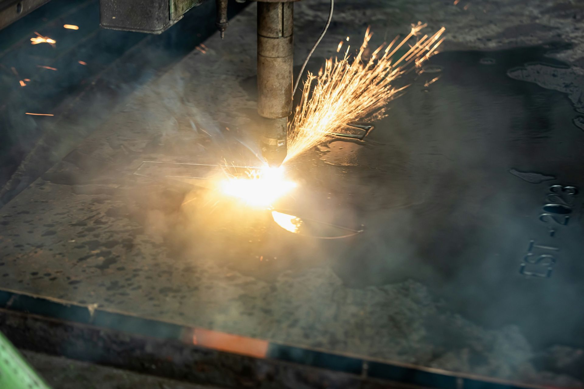 A machine is cutting a piece of metal with sparks coming out of it.