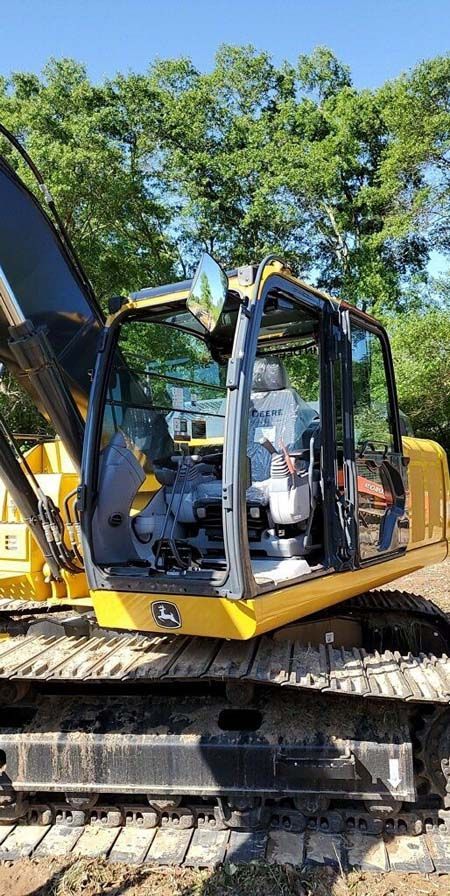A yellow and black excavator is parked on a dirt road.