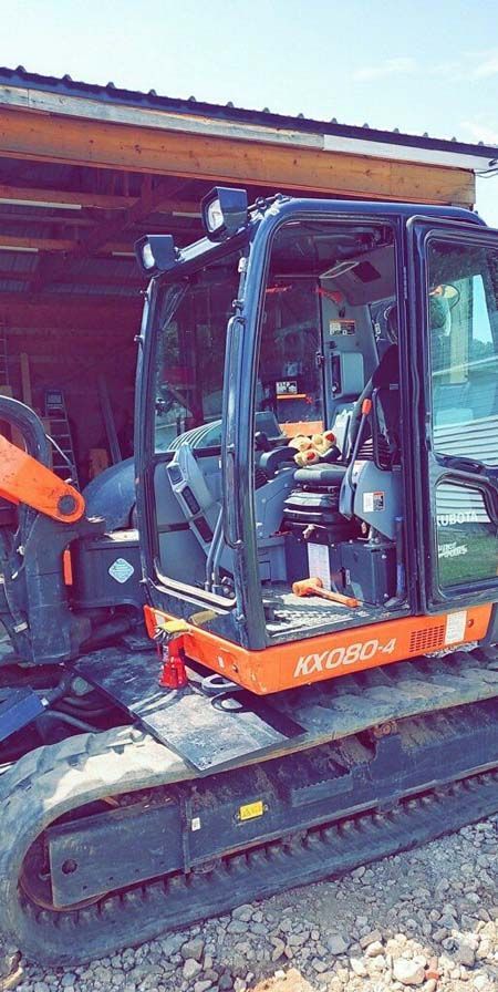 A small excavator is parked in front of a garage.