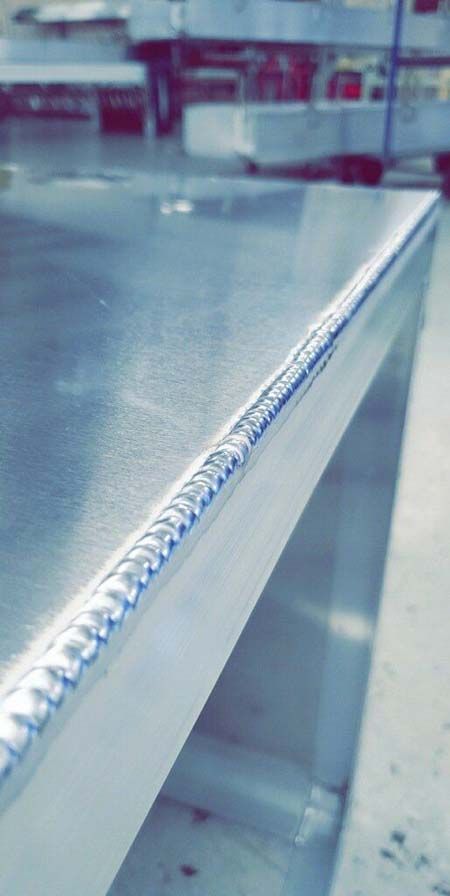 A close up of a stainless steel table with a welded edge.