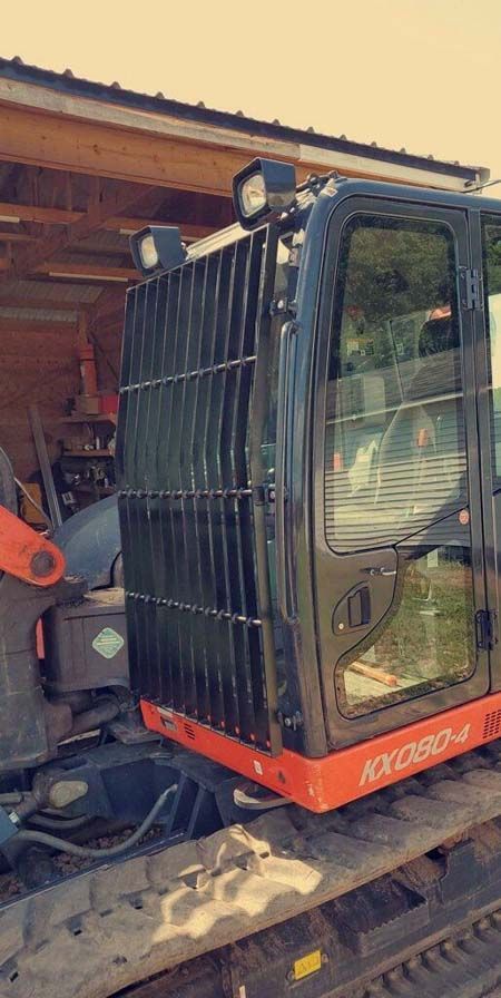 A small excavator is parked in front of a wooden building.