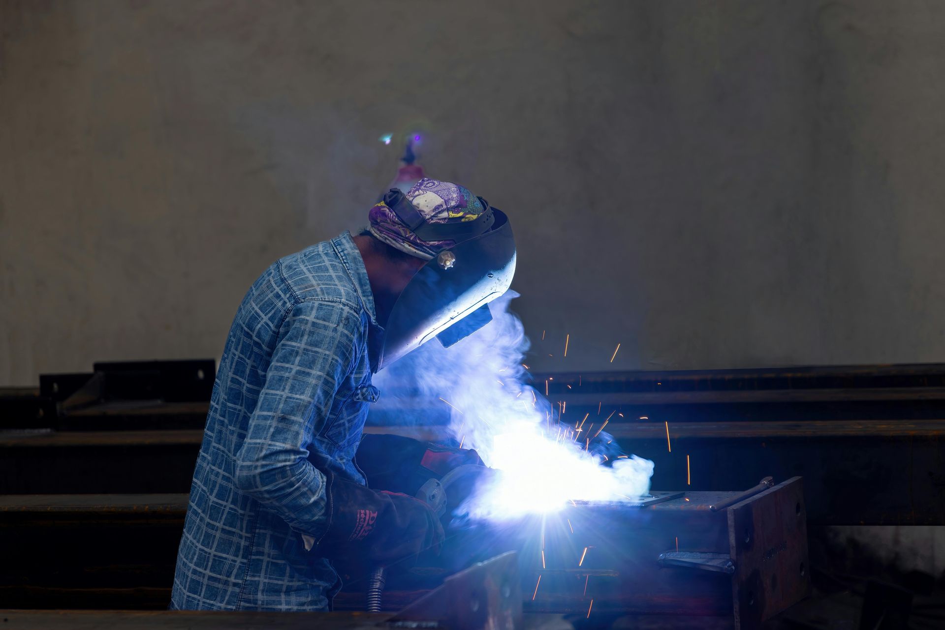A man is welding a piece of metal in a factory.