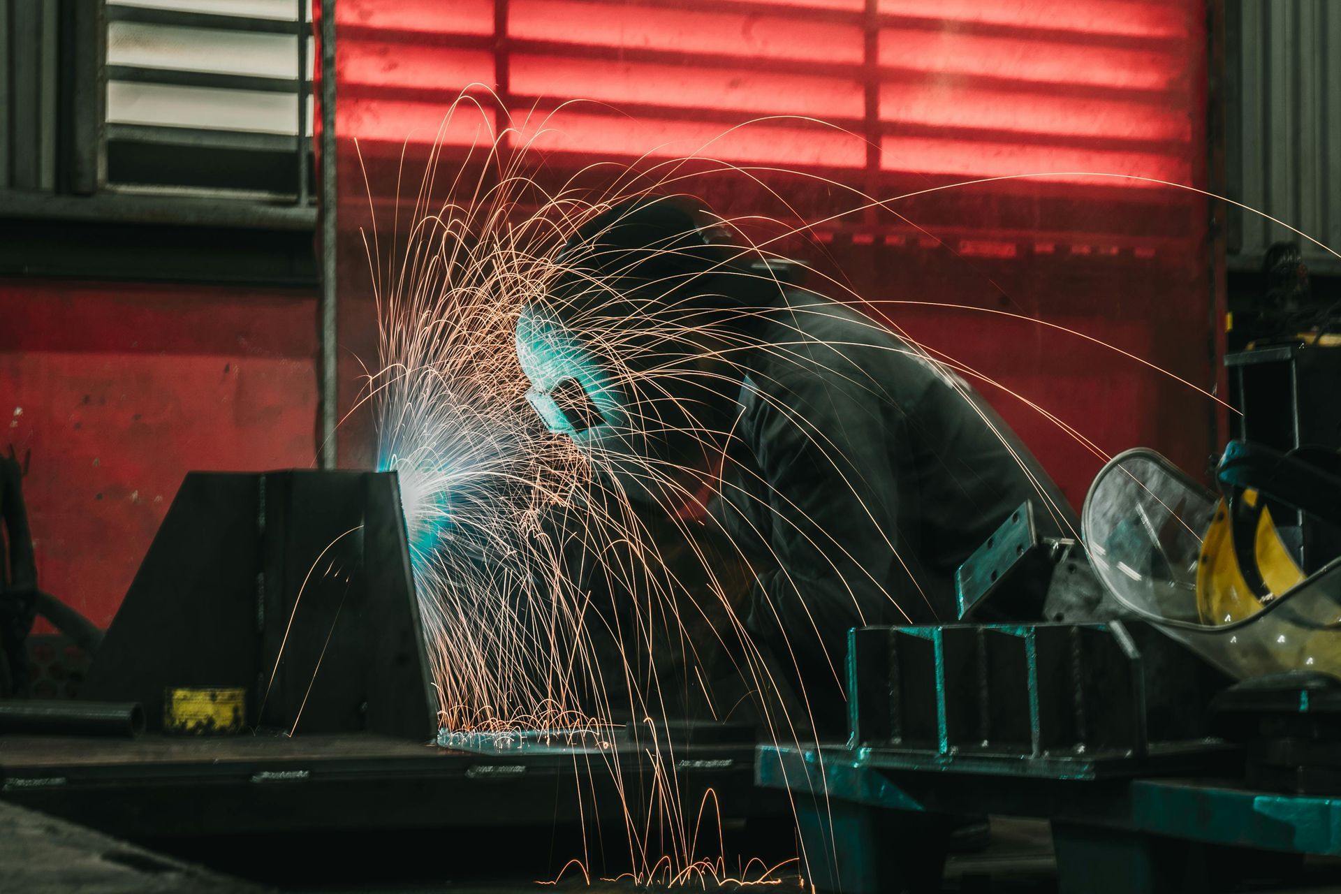 A man is welding a piece of metal in a factory.