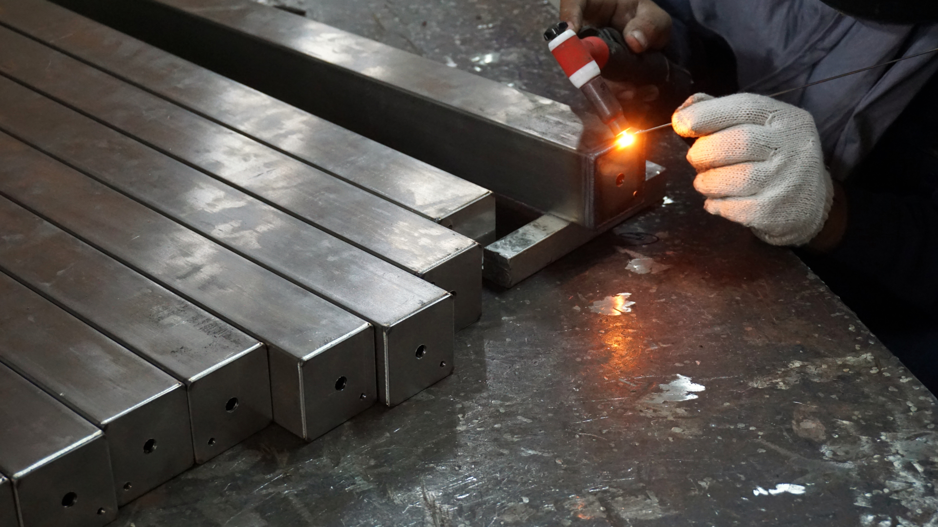 A man is welding a piece of metal in a factory