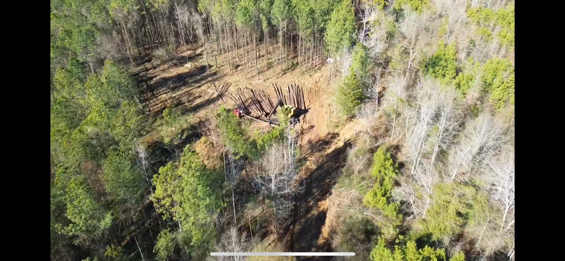 Aerial view of a hillside with patches of trees and visible brown earth.