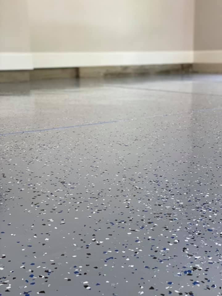 Grey speckled epoxy floor with white baseboard and wall.