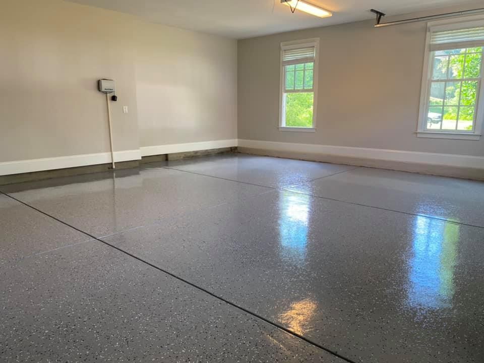 Empty garage with a shiny gray epoxy floor, light gray walls, and two windows.
