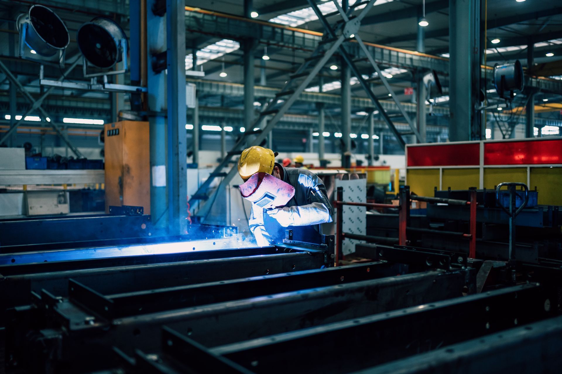 A young man is working in a factory workshop alone, mending an ornamental steel structure.