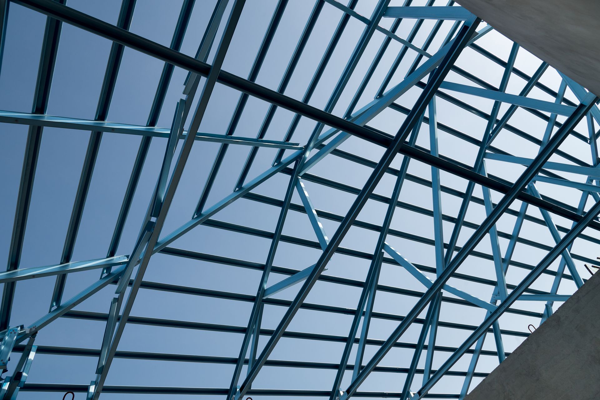 Structure of steel roof frame for building construction isolated on blue sky background.