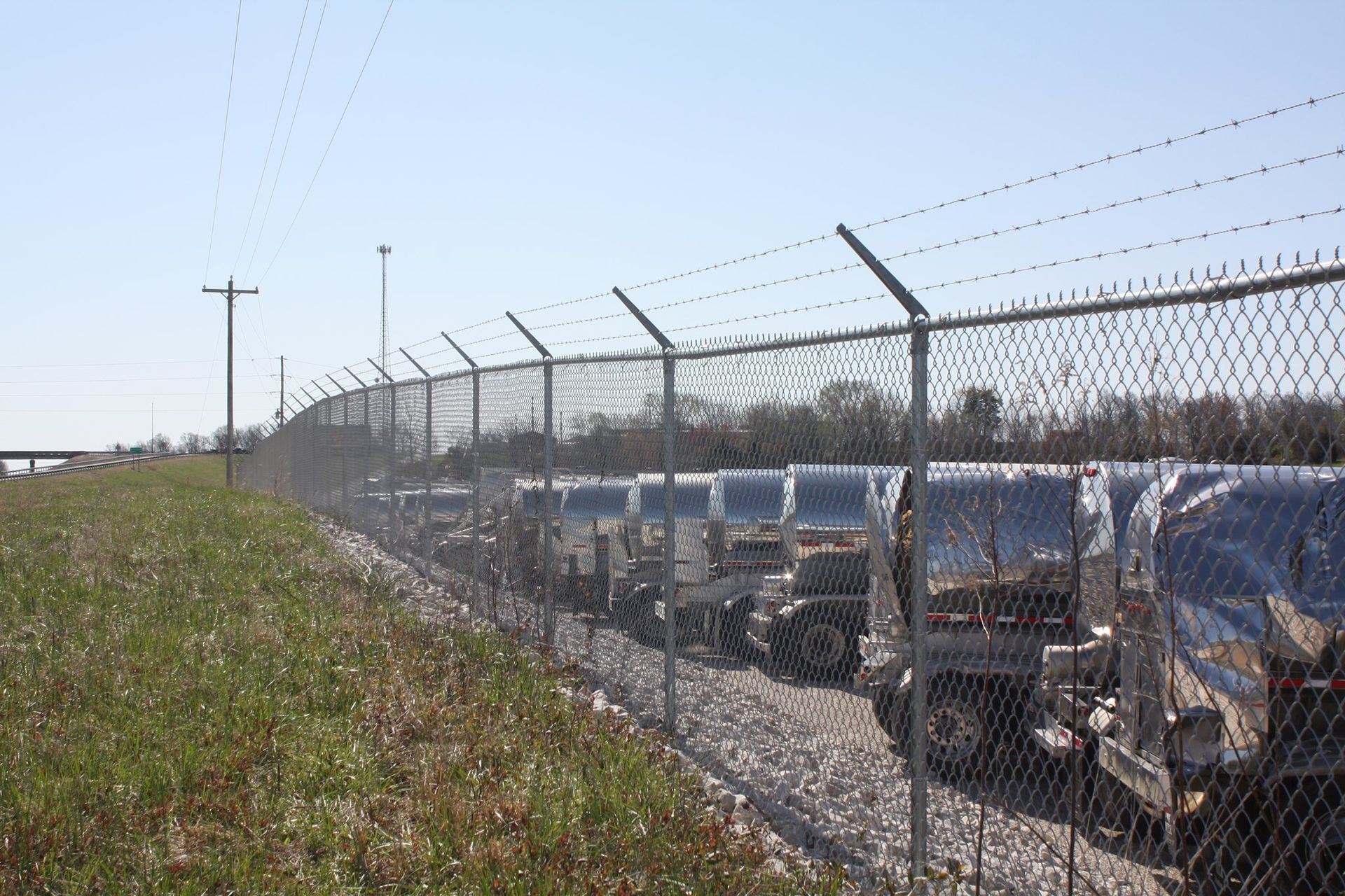 Rooftop HVAC units beside a chain-link fence under a clear blue sky