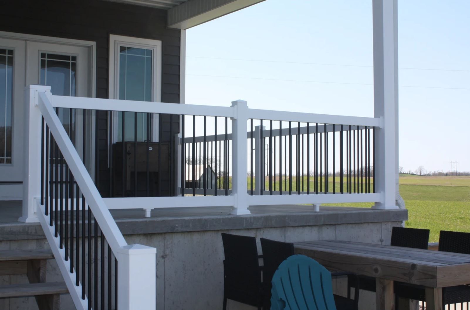 White-railed porch deck with stairs overlooking an open field on a sunny day