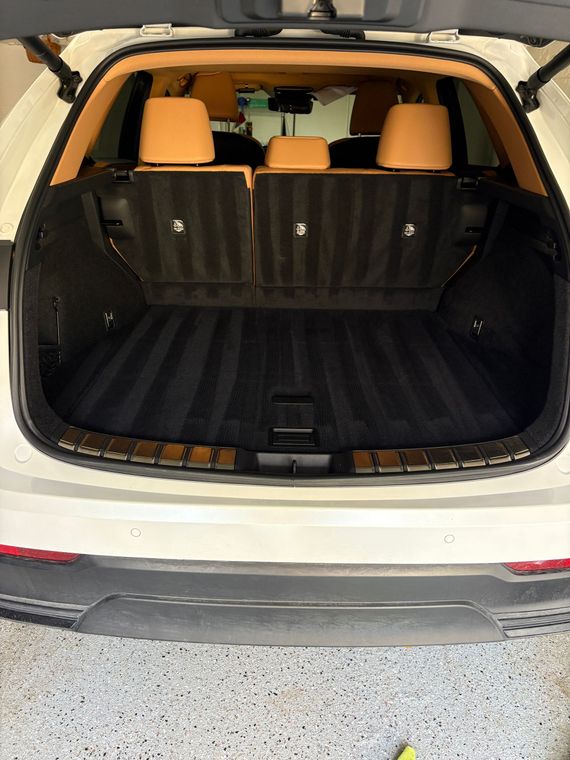 Open car trunk with black cargo mat and tan rear seats visible.