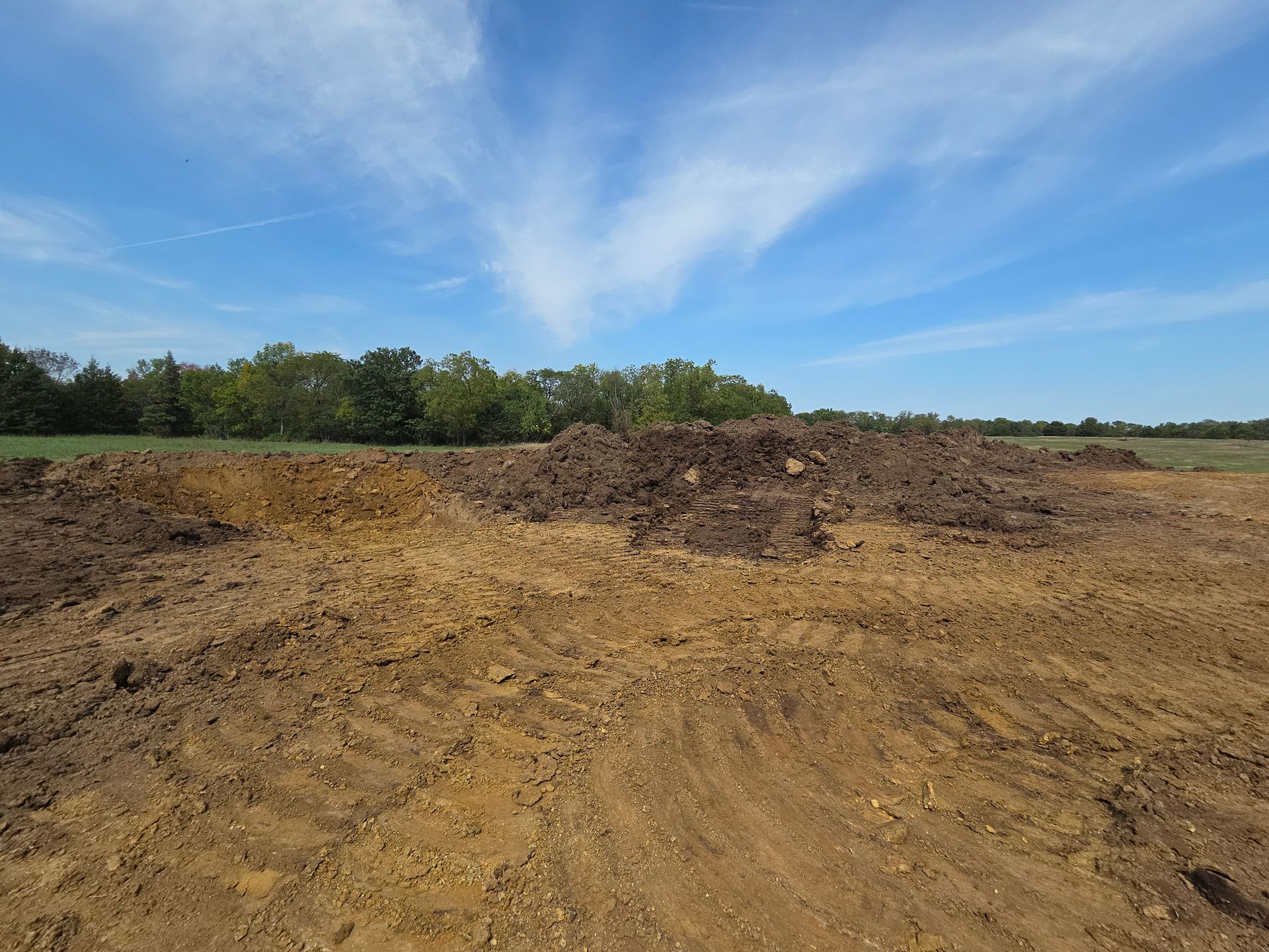 A bulldozer is cutting down trees in a dirt field.