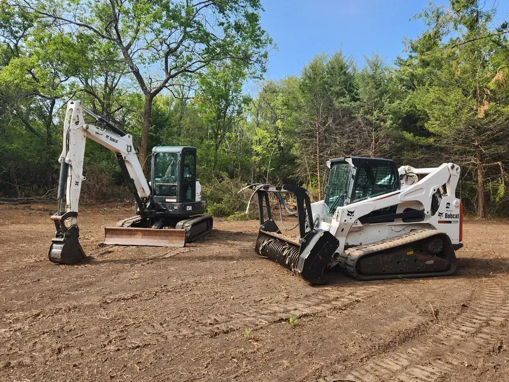 Two bulldozers are parked next to each other in a dirt field.