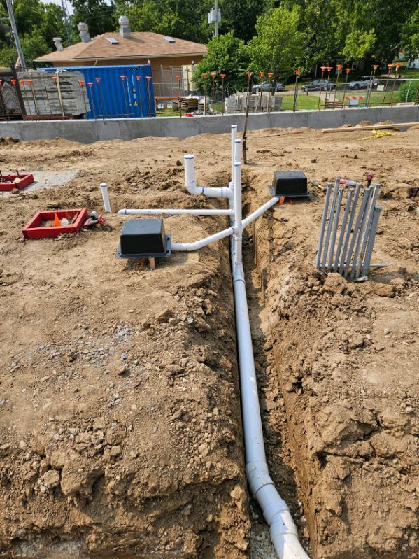 A drain pipe is being installed in the dirt on a construction site.