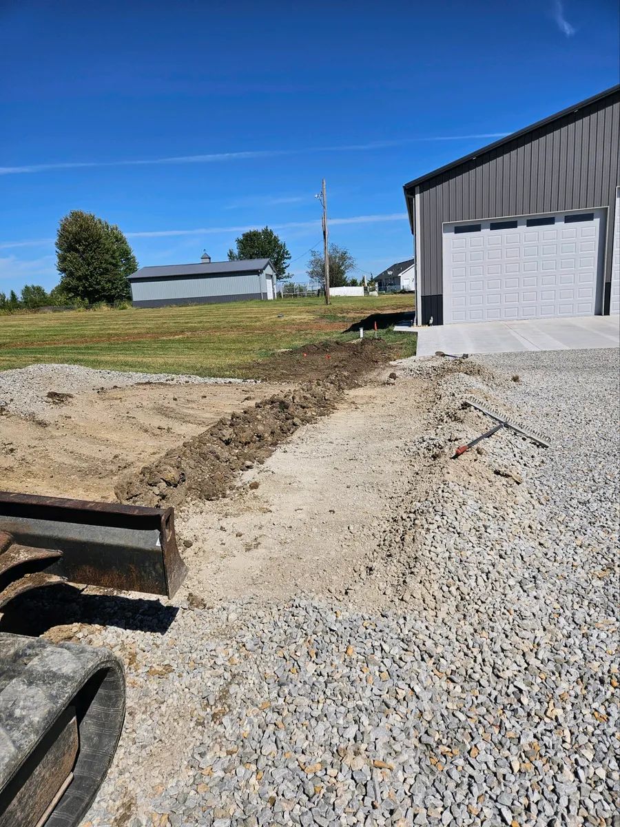 A bulldozer is sitting on a gravel road in front of a building.