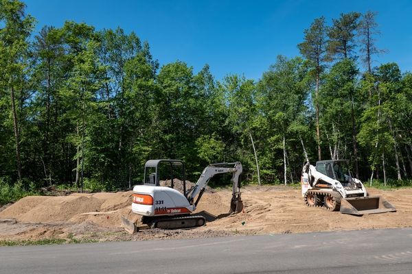A couple of construction vehicles are parked on the side of a road.