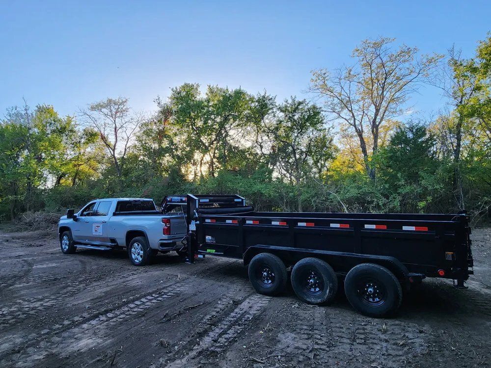 A truck is towing a dump trailer on a dirt road.