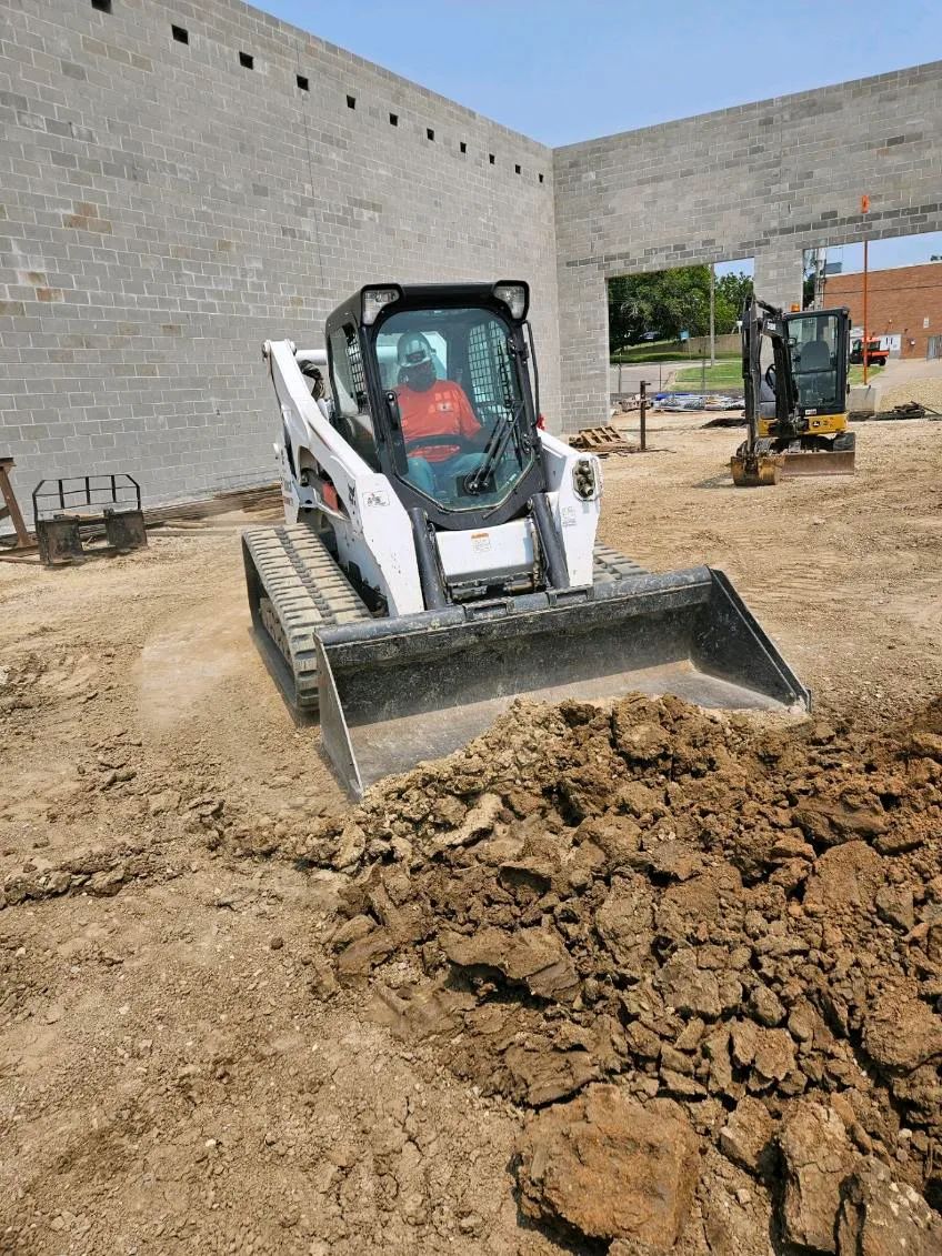 A bulldozer is moving dirt in front of a building under construction.