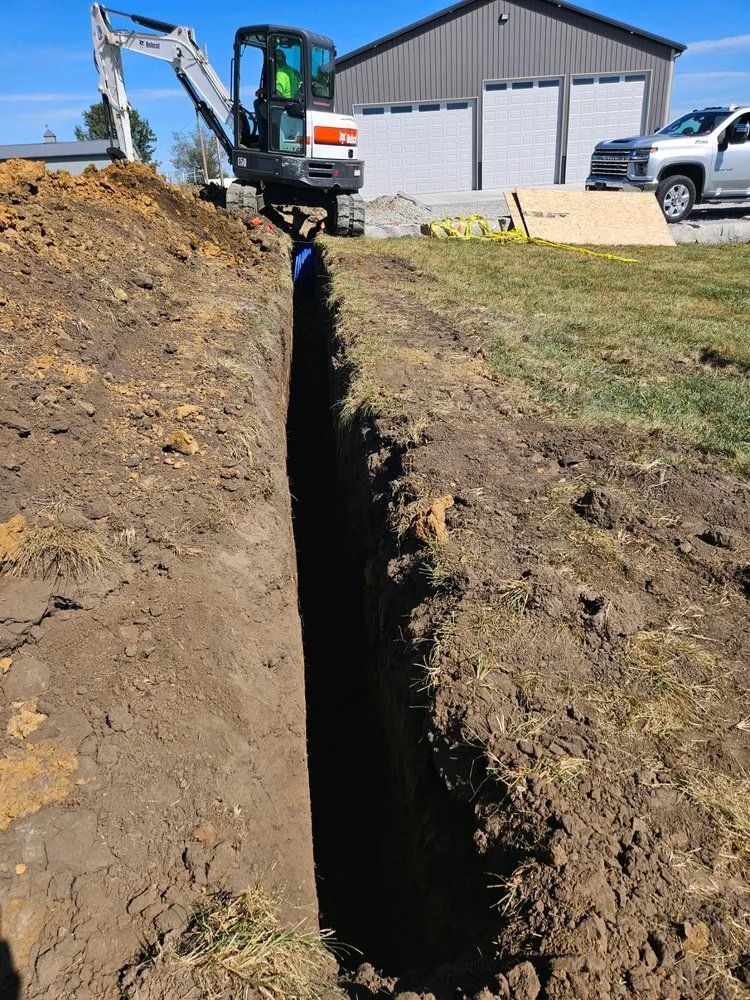 A small excavator is digging a trench in the dirt.