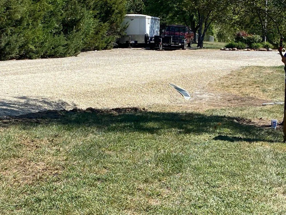 A truck is parked in a grassy area next to a tree.