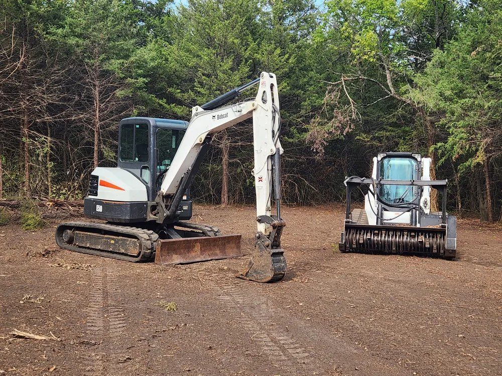 A bobcat excavator and a bulldozer are sitting in a dirt field.
