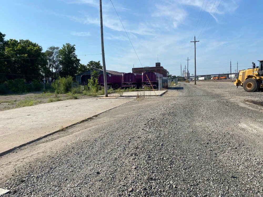 A gravel road with a purple train in the background