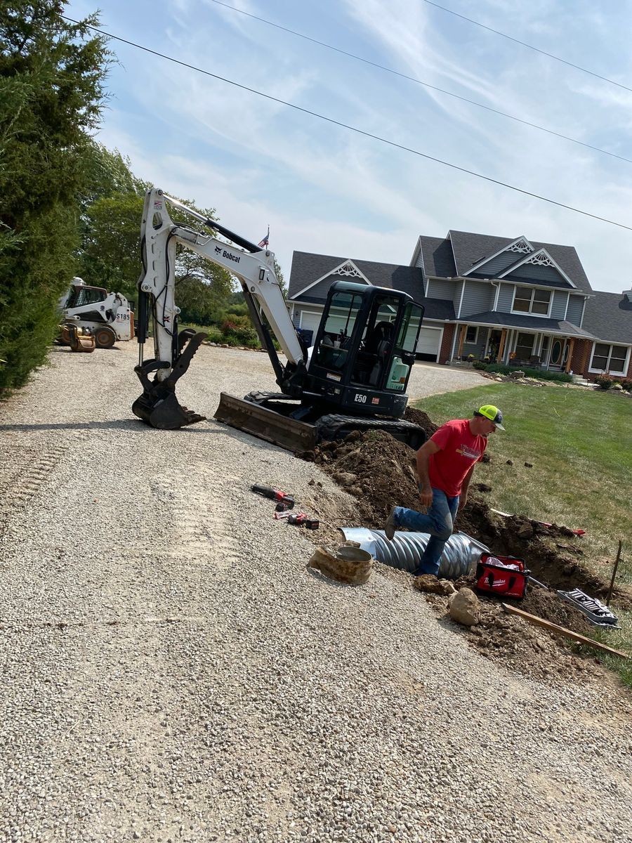A man is digging a hole in the dirt in front of a house.