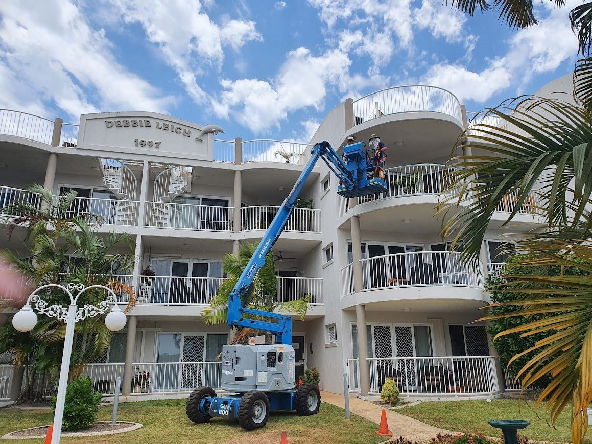 A man is using a crane to paint a building.