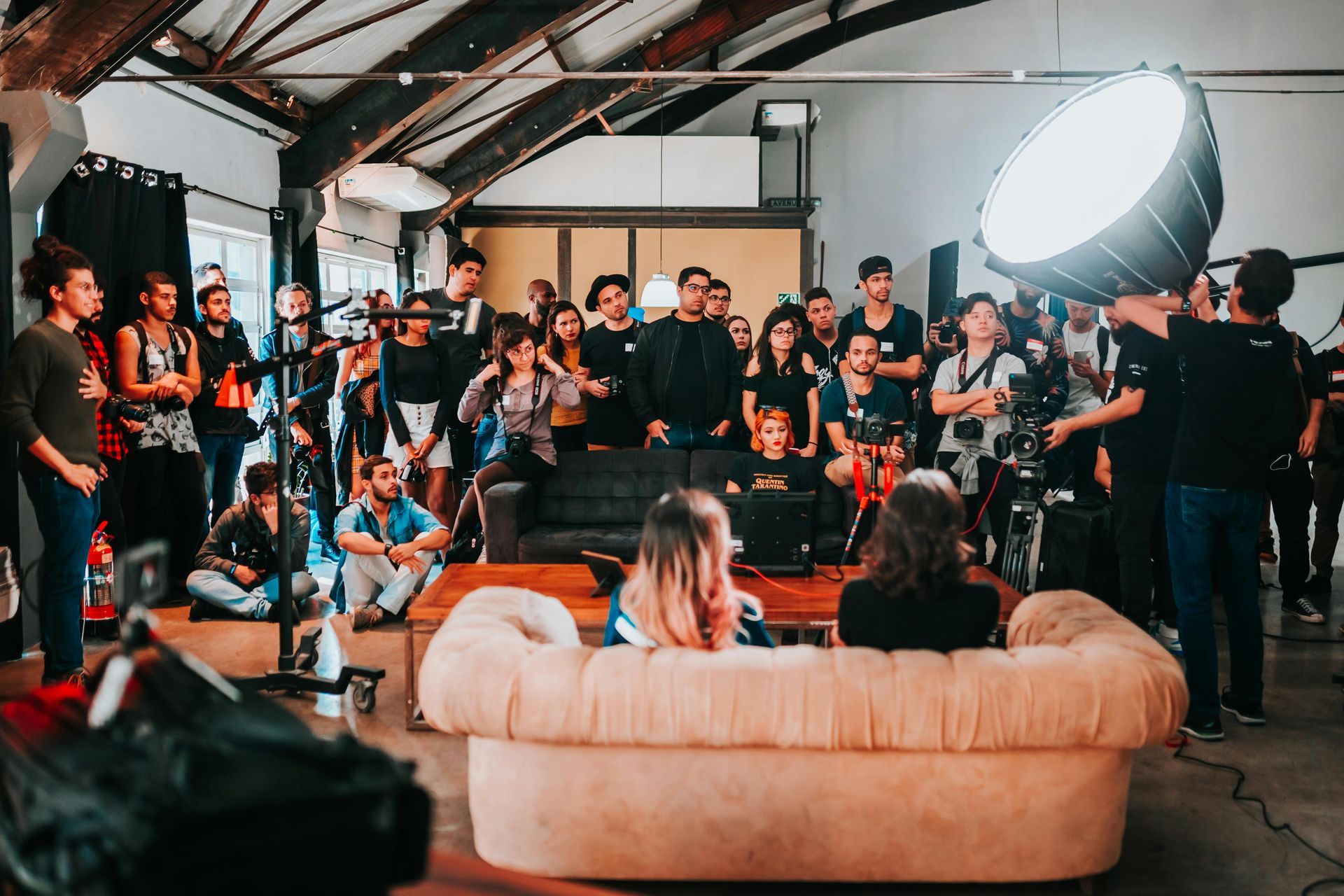 A group of people are sitting on a couch in front of a camera.