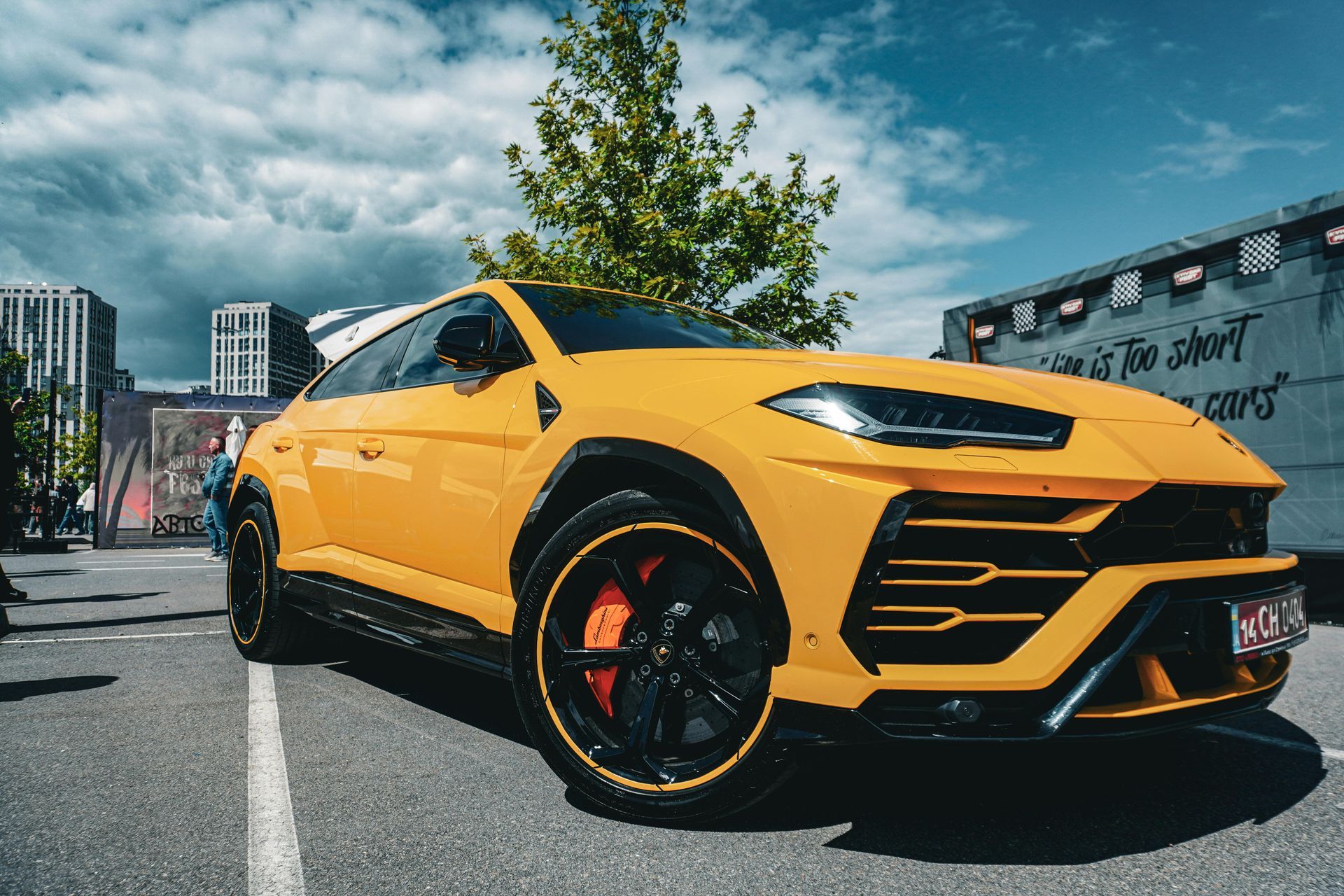 A yellow lamborghini urus is parked in a parking lot.