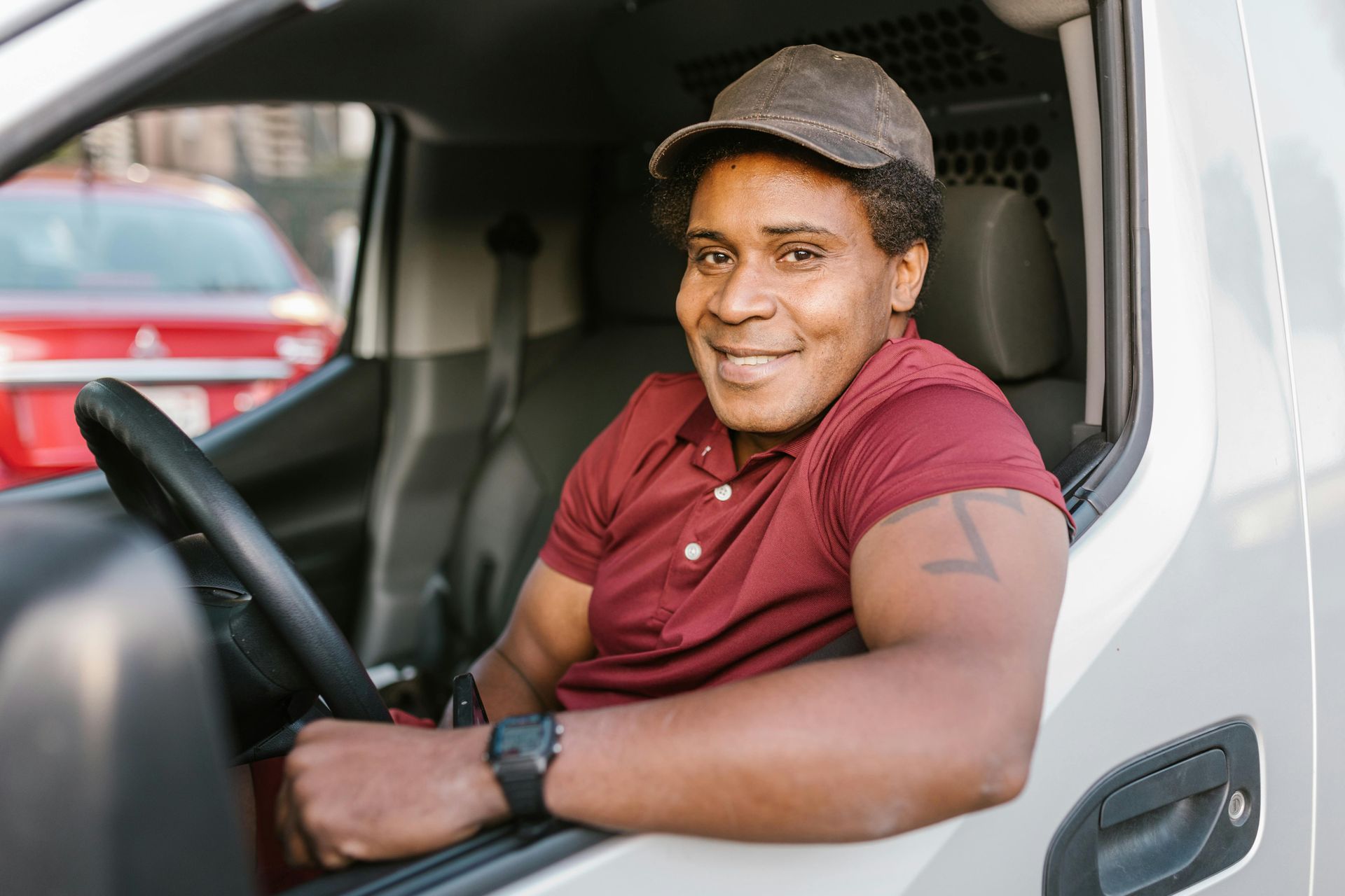 A man is sitting in the driver 's seat of a van and smiling.