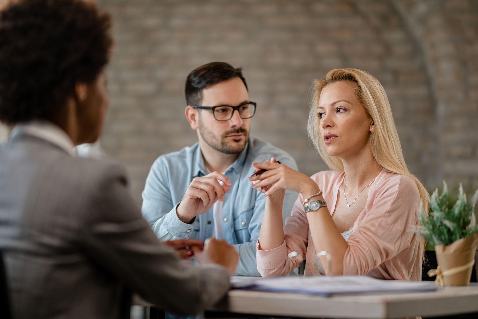 A man and a woman are sitting at a table talking to a woman.