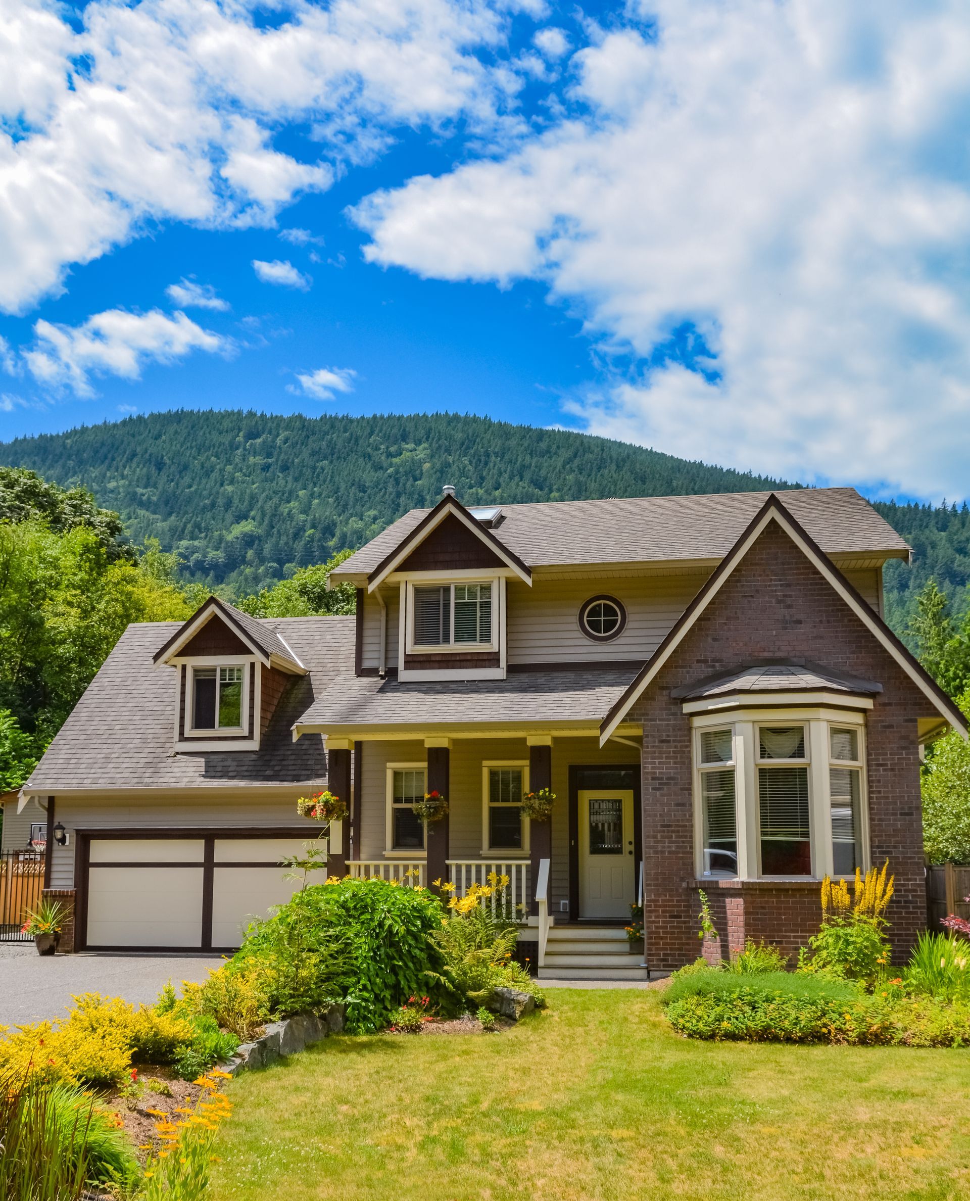 A large brick house is sitting on top of a lush green hillside.