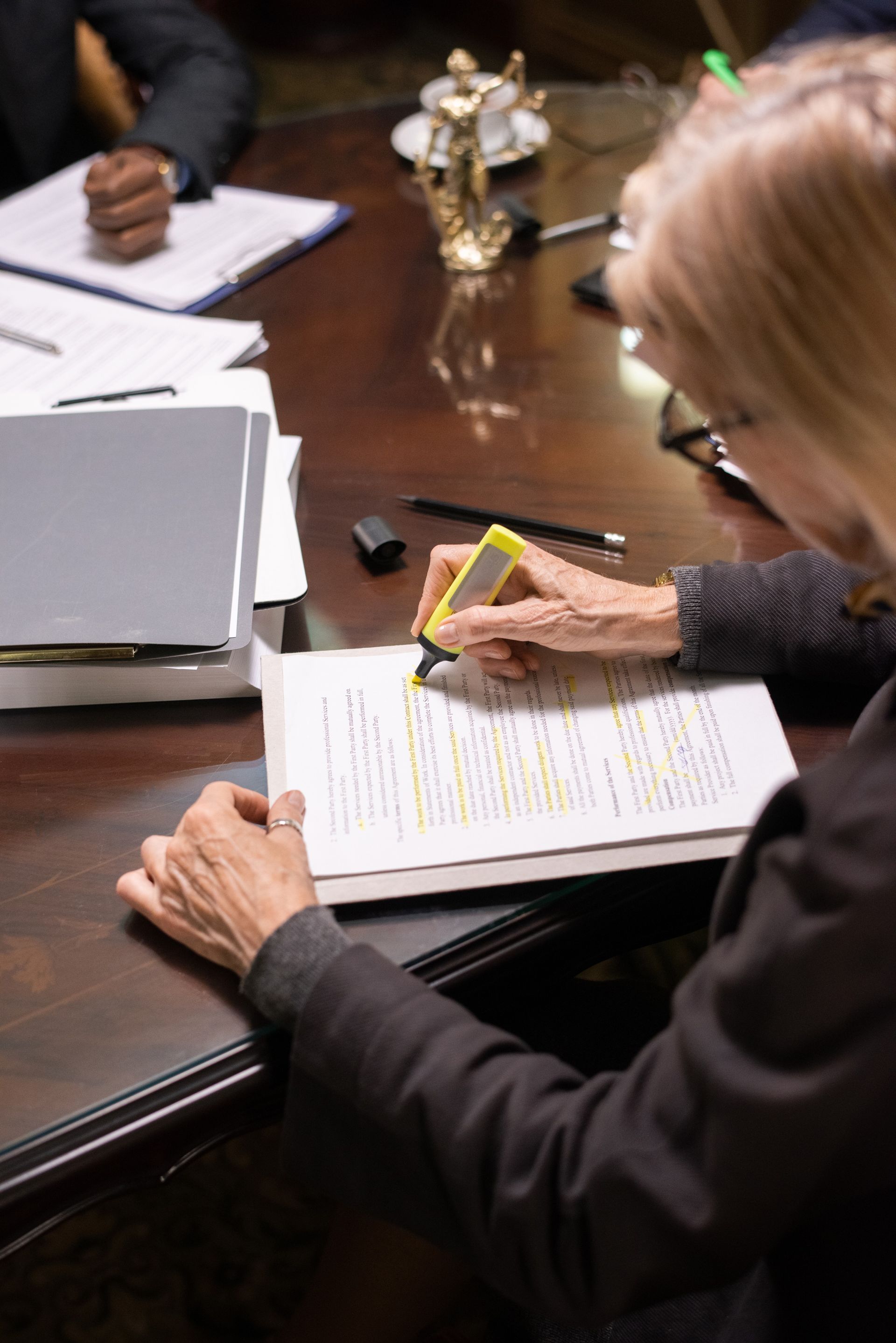 A woman is sitting at a table writing on a piece of paper.