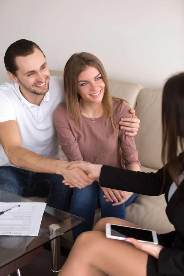 A man and woman are shaking hands with a woman while sitting on a couch.