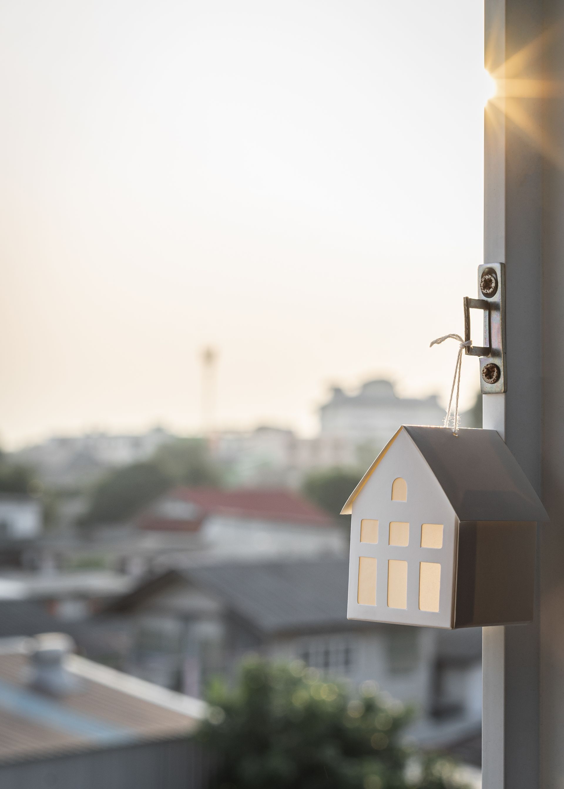 A small model house is hanging on a pole.