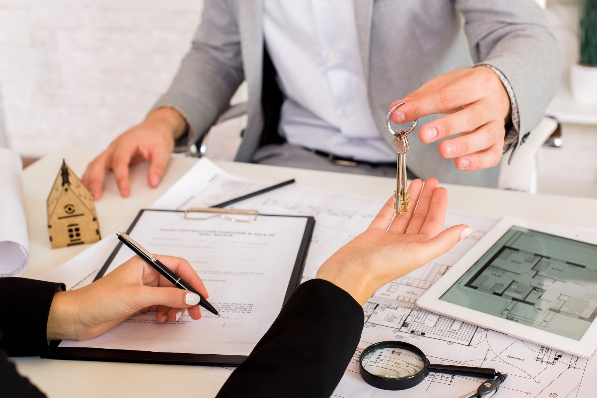 A man is giving a woman a set of keys while she signs a document.