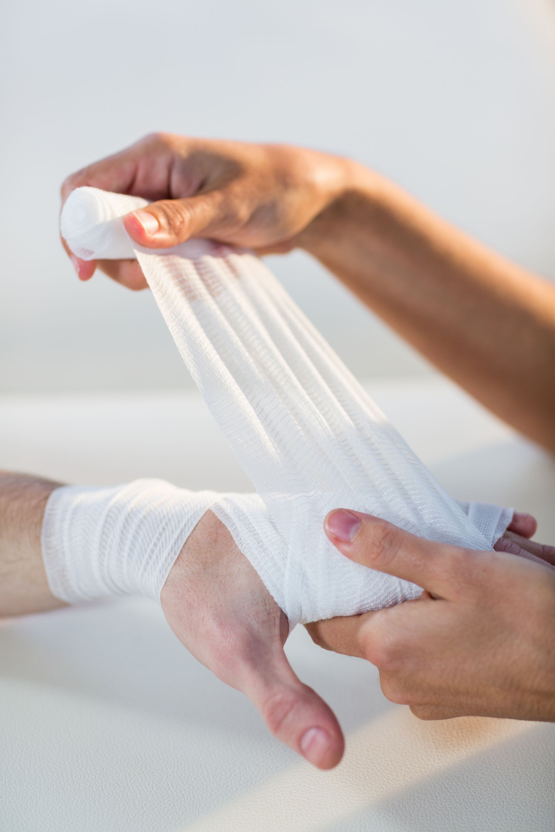 Physiotherapist putting bandages on a patient hand