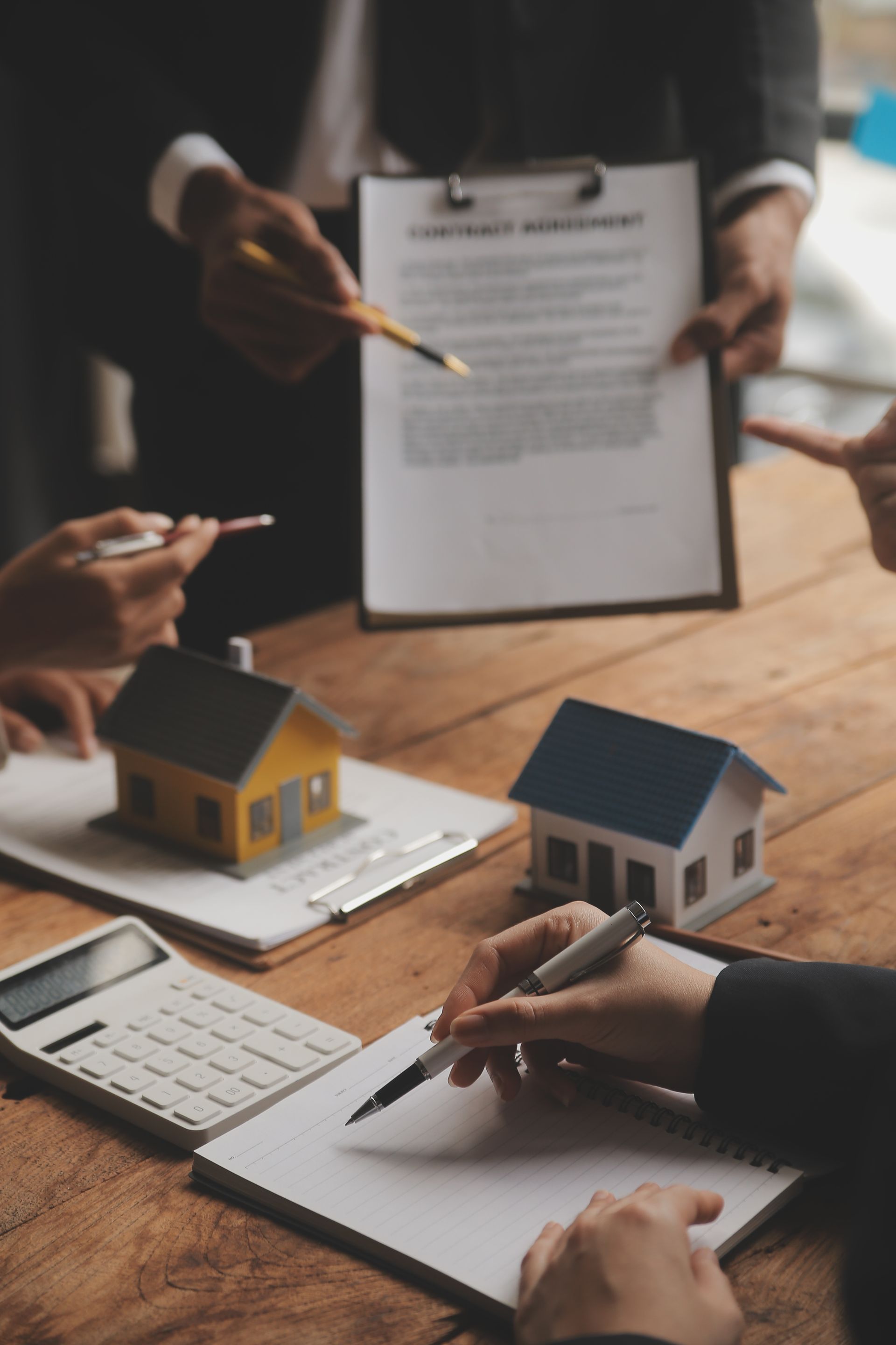 A group of people are sitting at a table looking at papers and houses.