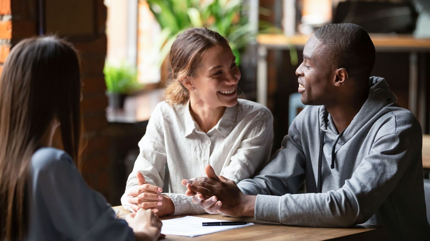 A man and a woman are sitting at a table talking to each other.