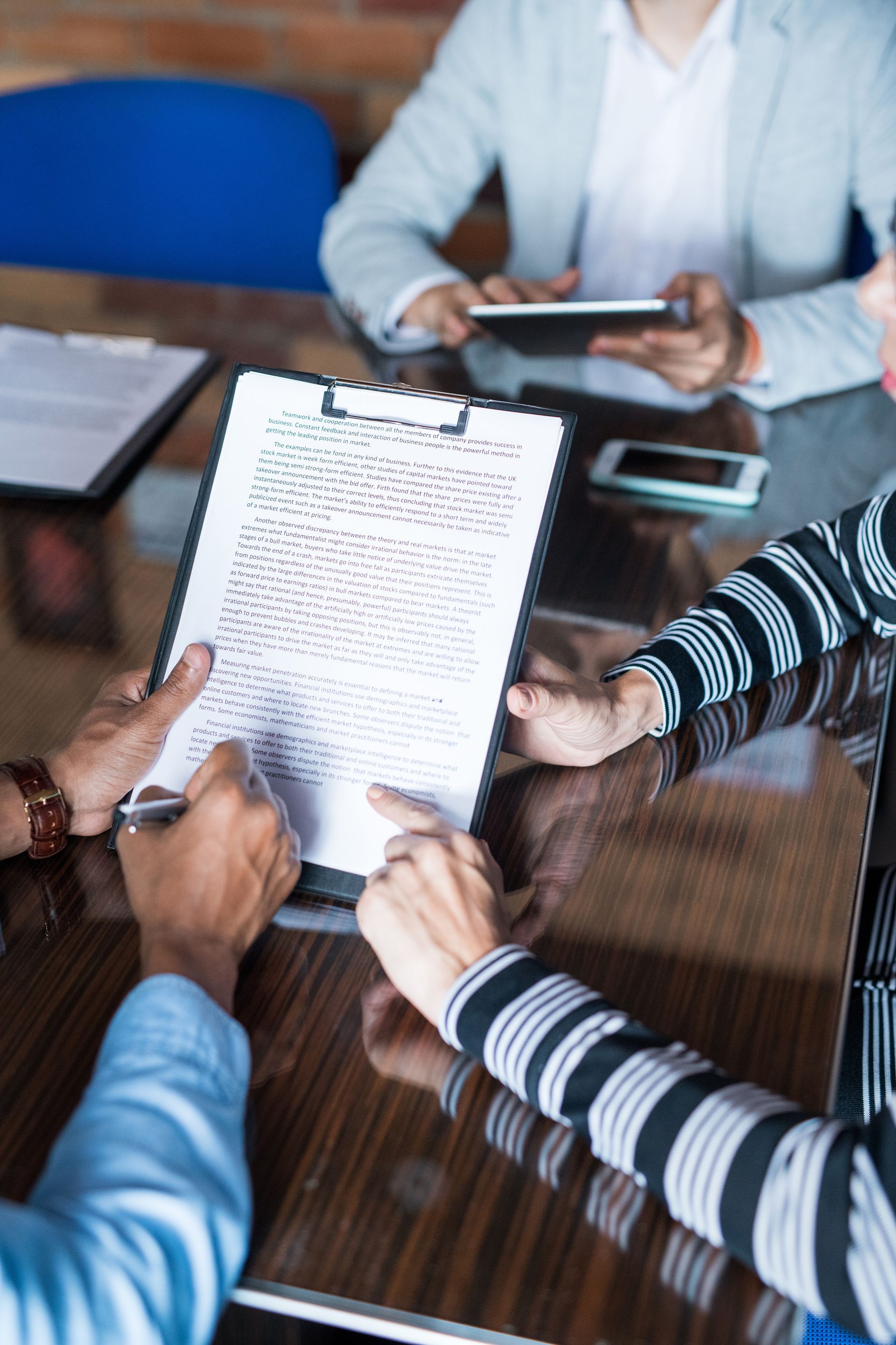 A group of people are sitting around a table looking at a clipboard.