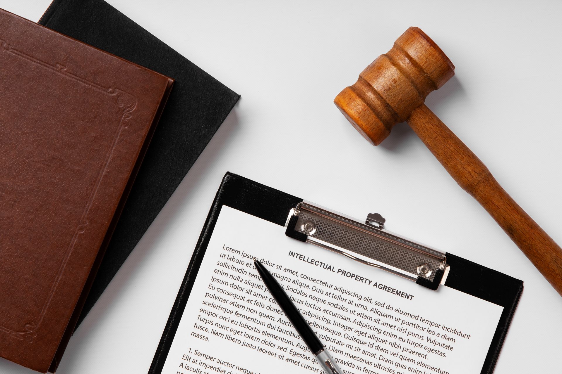A wooden judge 's gavel is sitting next to a clipboard with a pen on it.