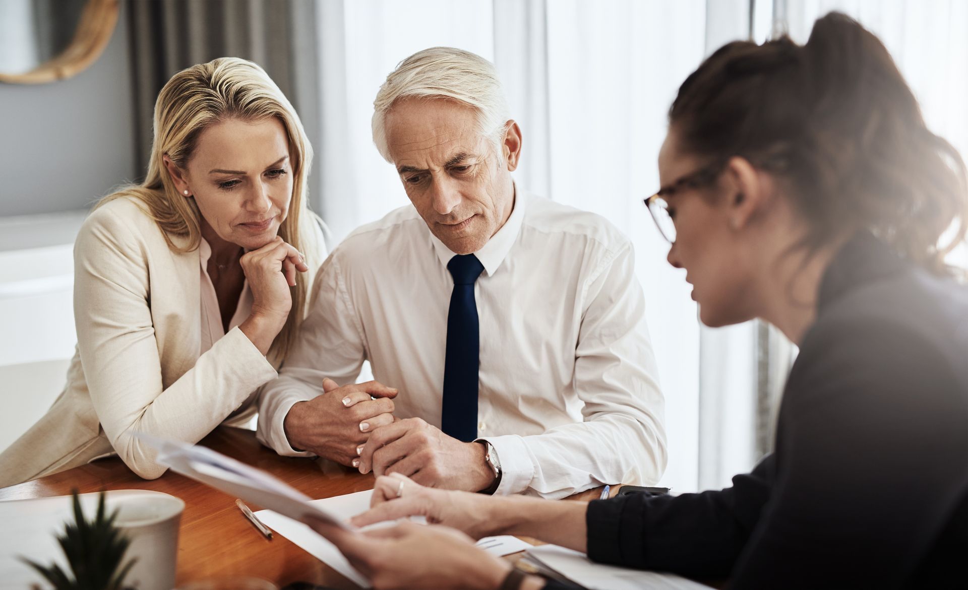 A man and a woman are sitting at a table talking to a woman.