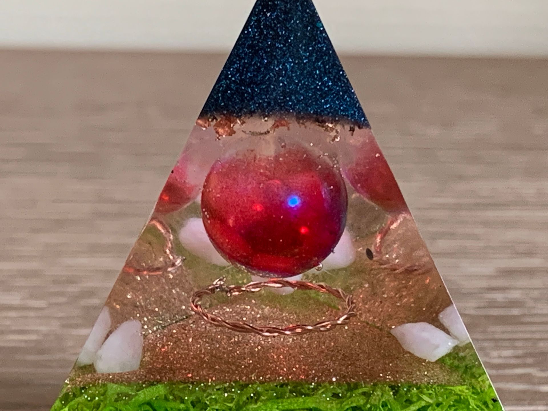 Orgonite. Een piramide met een rode bal in het midden op een tafel.
