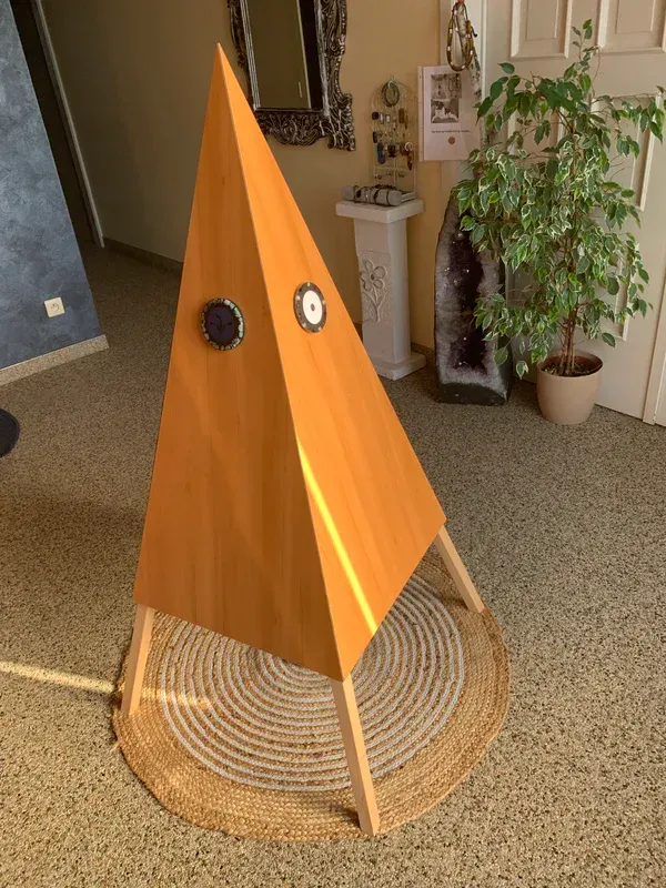 Core-piramide. Een houten piramide staat op een tapijt in een kamer