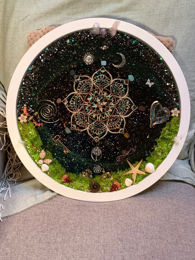 Een rond orgonite-werk met een mandala erop.