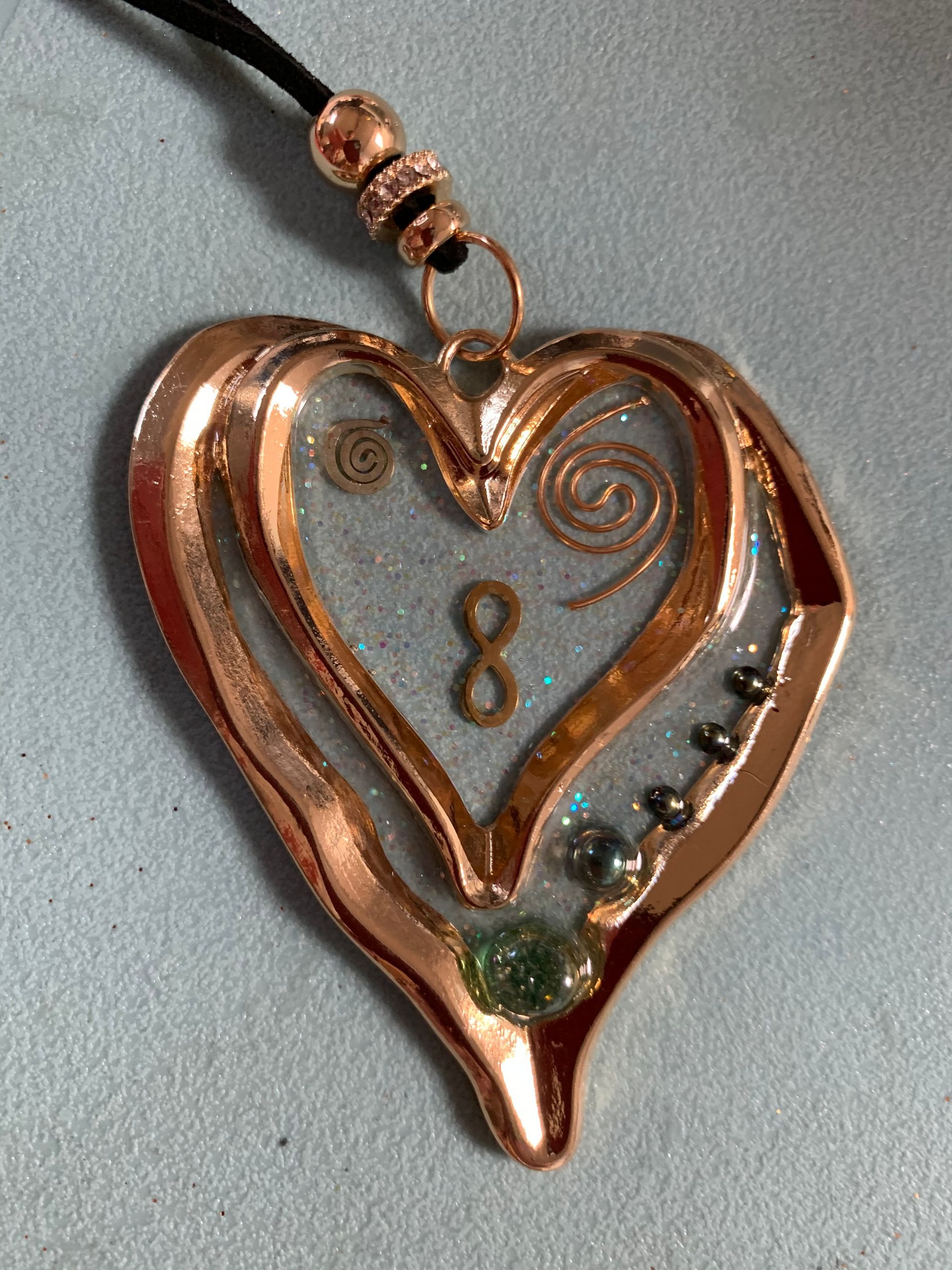 Orgonite. Een hartvormige hanger met het getal 8 (infiniti) erop