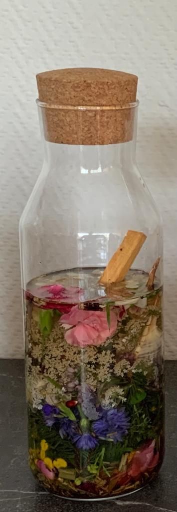 Agua de Florida. Een glazen fles gevuld met water en bloemen met een kurken deksel.