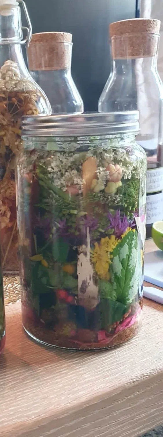 Agua de Florida. Op een houten tafel staat een pot gevuld met bloemen en groenten.